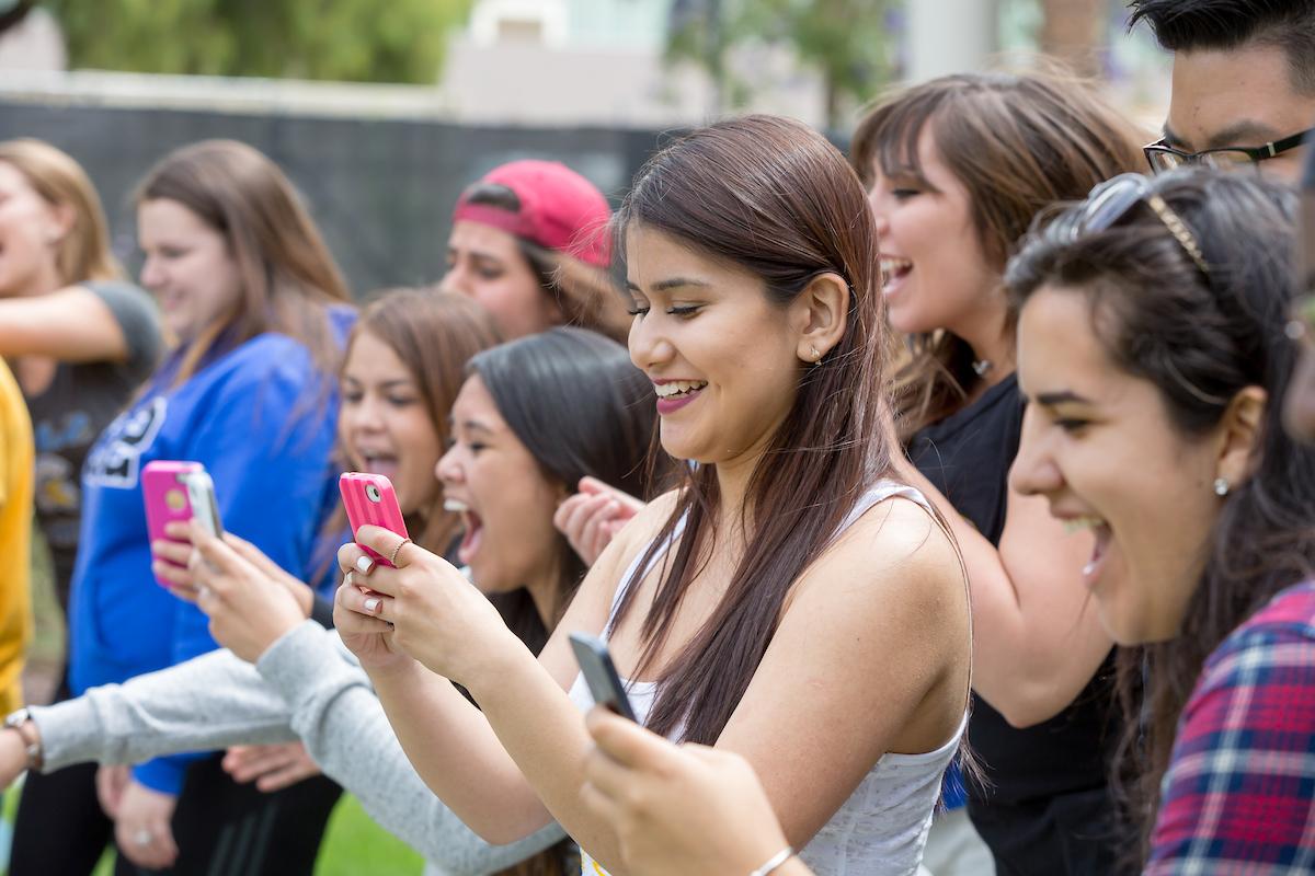 Several students appear excited, all viewing their cellphones.