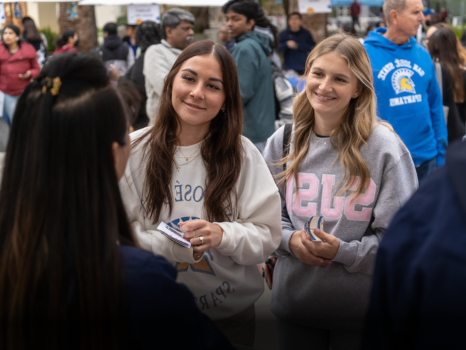 Two students speaking with college vendor.