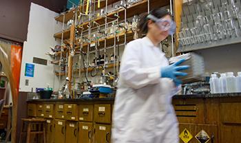 battery scientist in lab gear carries things in lab