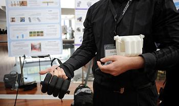 closeup of prosthetic hand on top of real hand with scientific poster in background